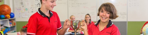 two students holding golden cup